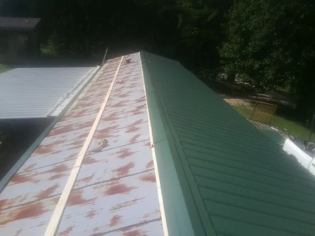 Old rusted panels beside newly installed green metal roofing — Wind Damage Roof Repair by Roofing Brothers in Anatone