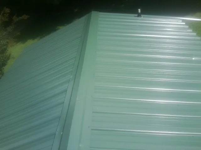 New green metal panels meeting at the ridge of a roof — Flat Roof Repair work by our crew in Anatone
