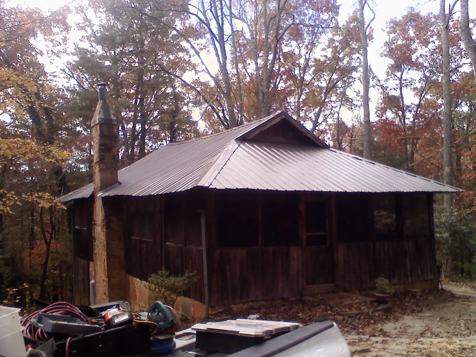 Brown metal hip roof on an old cabin with a stone chimney in Anatone