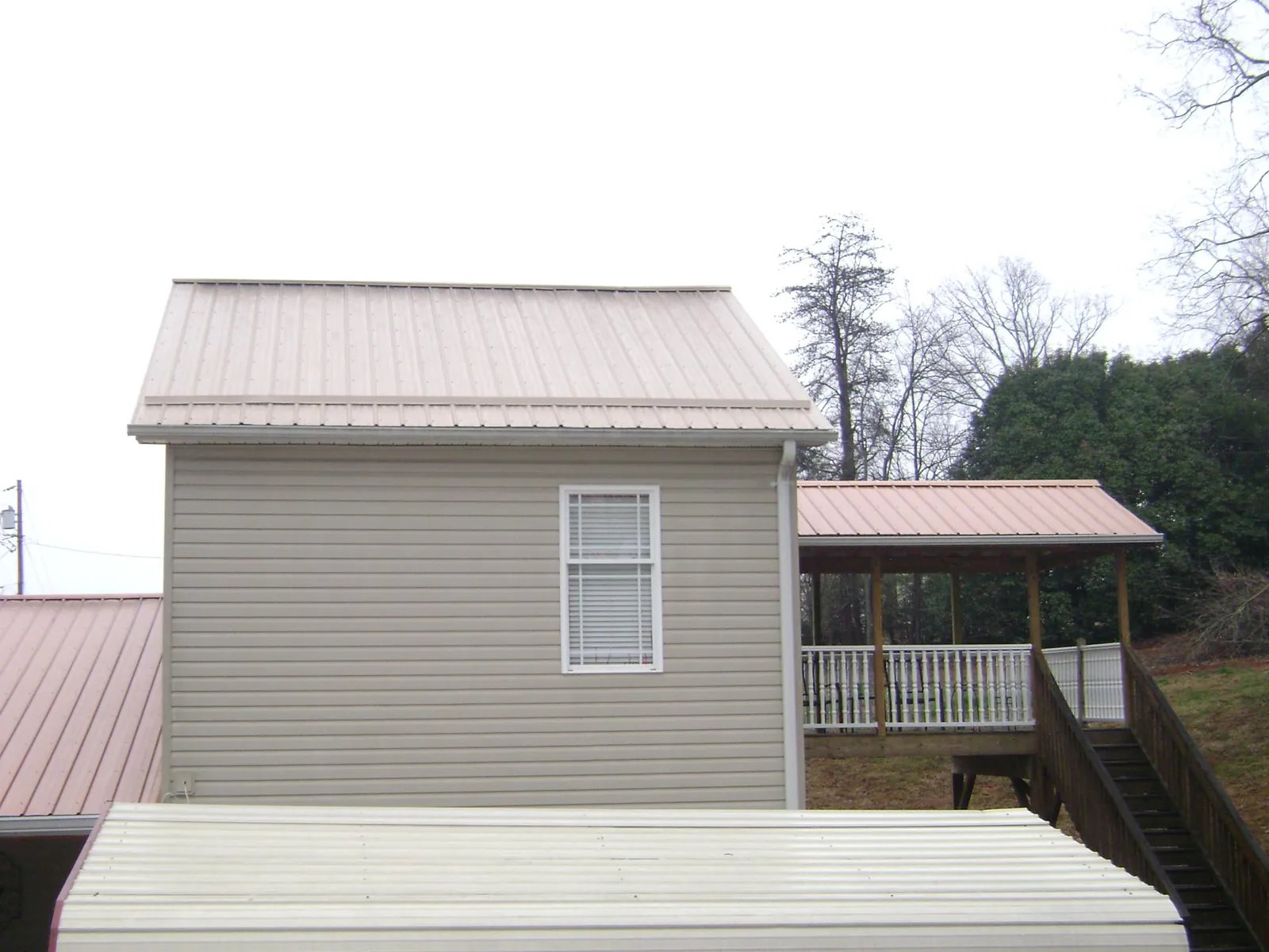 Tan metal roofs on a two story addition and attached porch, from a Roof Replacement job in Anatone