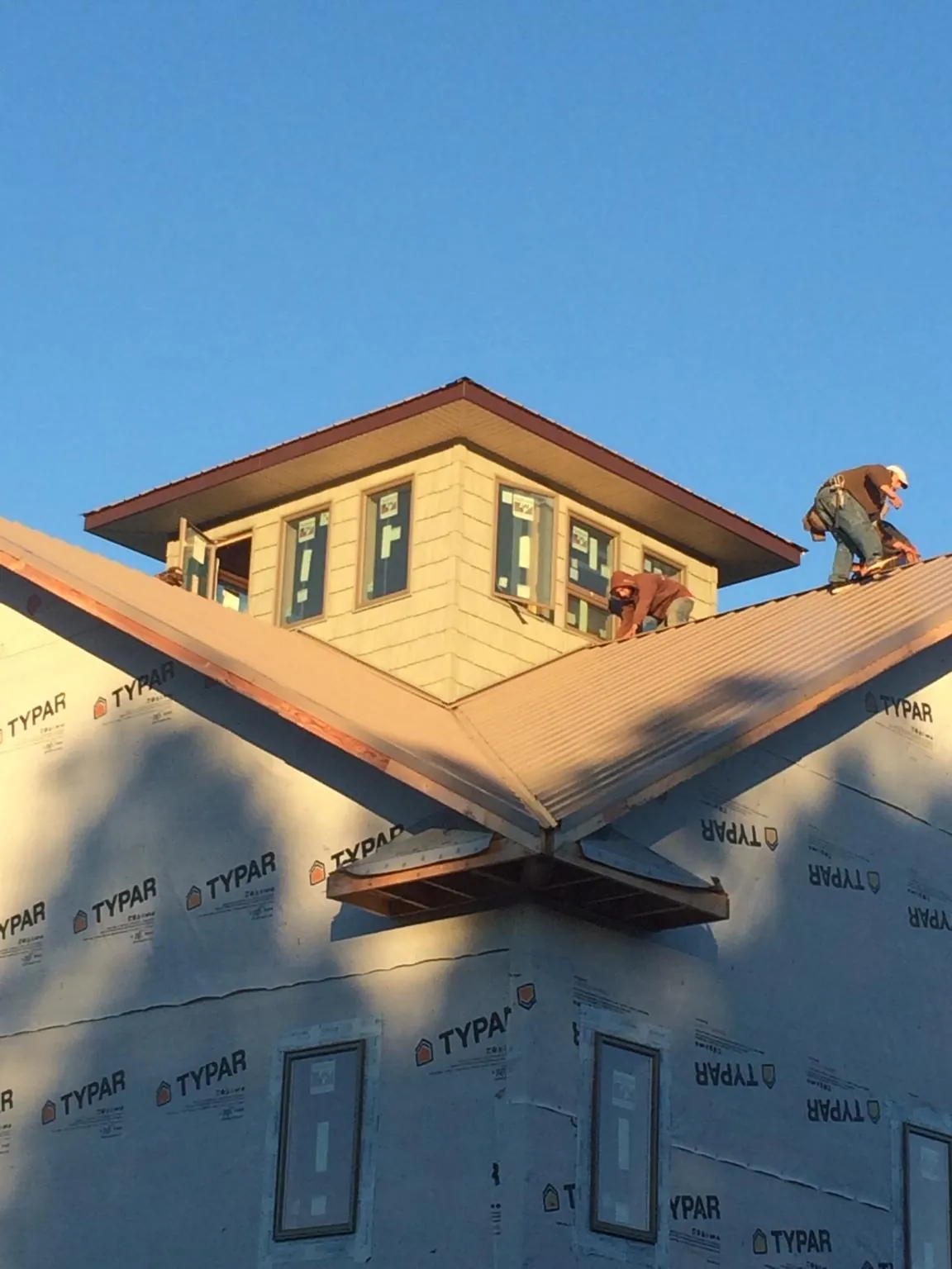 Roofers working around a rooftop cupola on a new metal roof at sunset — Roof Waterproofing in Anatone by Roofing Brothers